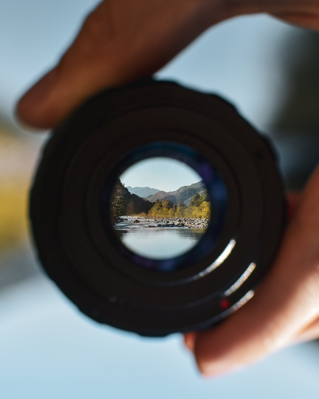 Looking through a camera lens at a sharply focused river and mountain landscape