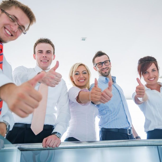 A team of smiling business people showing thumbs up
